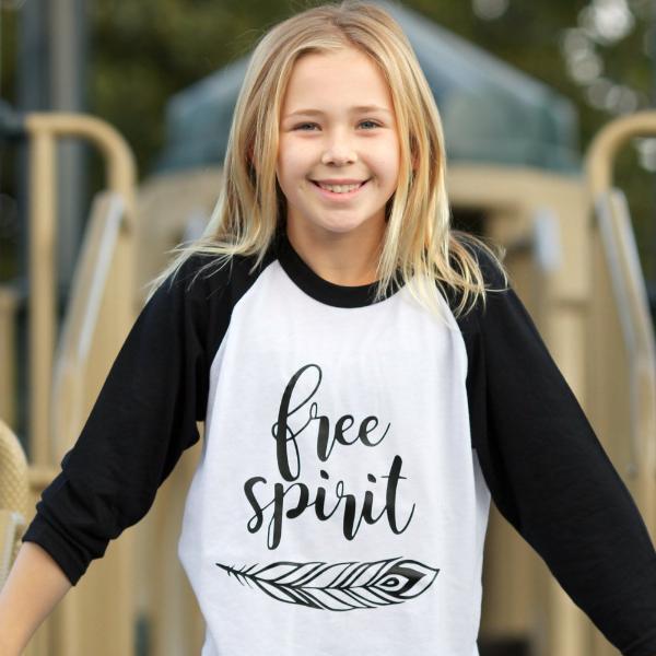 Little girl wearing black sleeve raglan that says Free Spirit with feather below words in black